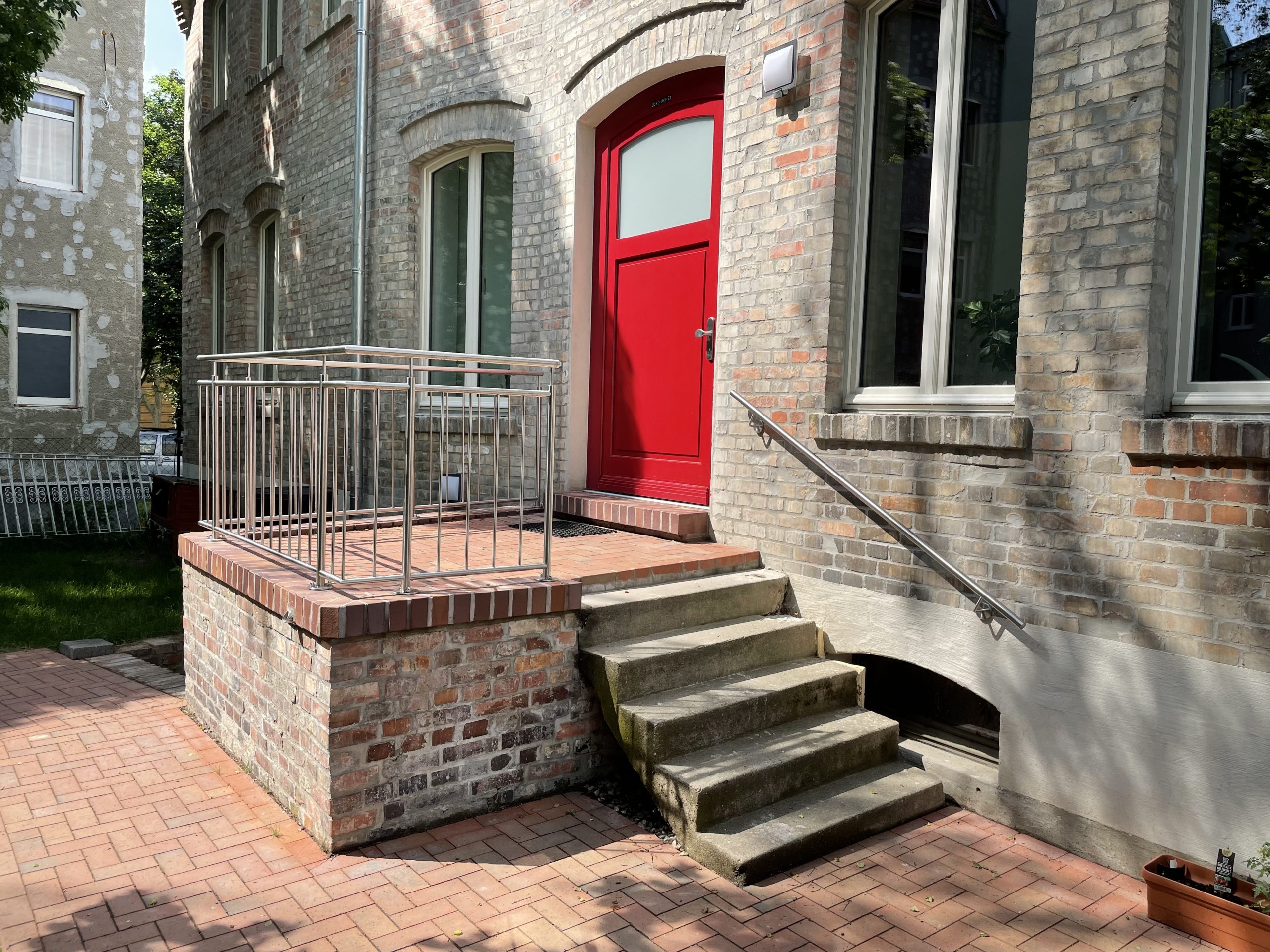 Fotografie der steinernen Eingangstreppe und der roten Eingangstür des Hinterhauses im Glauchaviertel